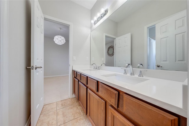 full bathroom with a sink, baseboards, double vanity, and tile patterned floors