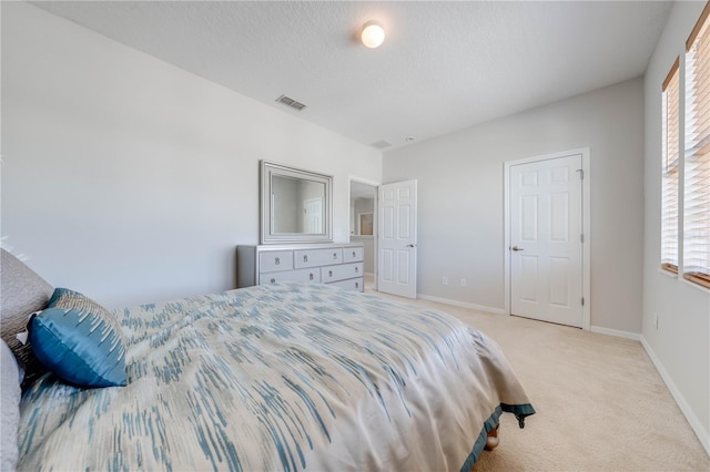 bedroom with visible vents, light carpet, a textured ceiling, and baseboards