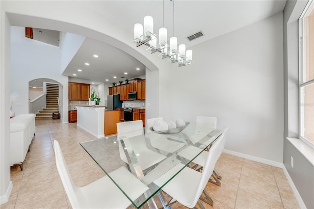 dining room with baseboards, visible vents, light tile patterned flooring, arched walkways, and a notable chandelier