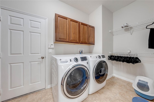 washroom featuring baseboards, cabinet space, and independent washer and dryer