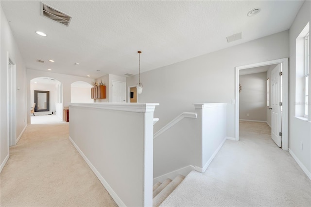 hall featuring recessed lighting, an upstairs landing, visible vents, and light carpet