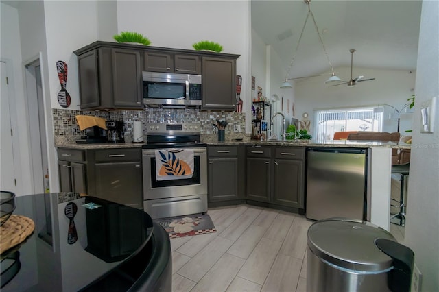 kitchen with light stone countertops, visible vents, a peninsula, appliances with stainless steel finishes, and backsplash