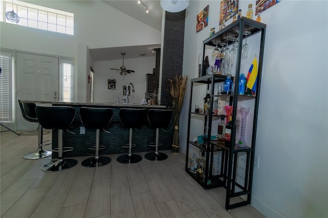 bar with a sink, high vaulted ceiling, indoor wet bar, and wood tiled floor