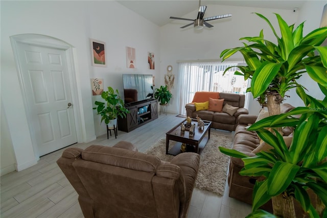 living area featuring baseboards, high vaulted ceiling, a ceiling fan, and wood finished floors