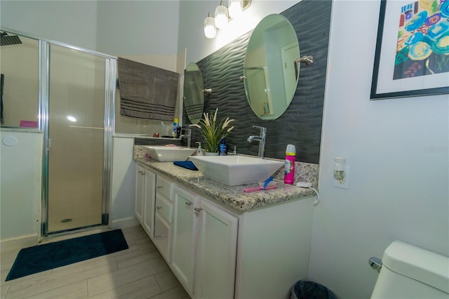 bathroom featuring double vanity, toilet, a stall shower, and a sink