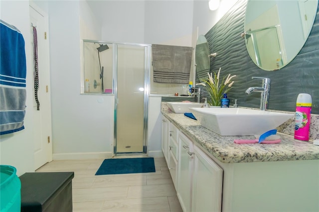 bathroom featuring double vanity, a shower stall, and a sink