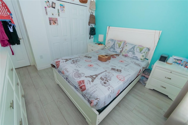 bedroom with wood finish floors, a closet, and baseboards