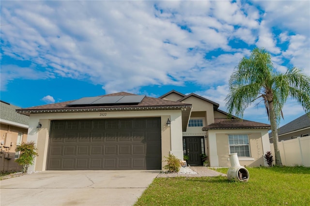 view of front of home with stucco siding, driveway, fence, an attached garage, and solar panels