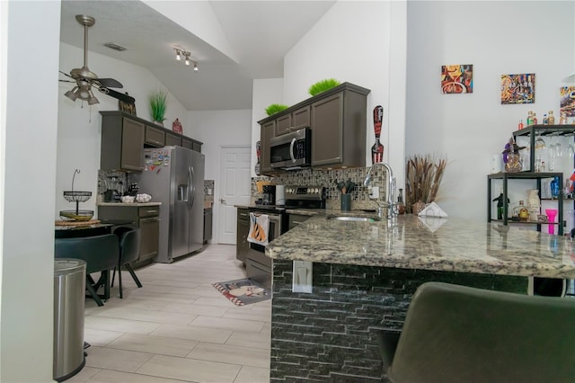 kitchen featuring visible vents, backsplash, appliances with stainless steel finishes, a peninsula, and stone counters