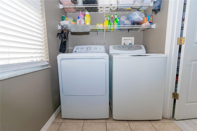 laundry room with tile patterned floors, baseboards, washing machine and dryer, and laundry area