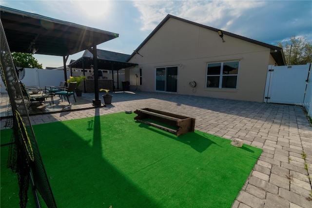 back of house with a patio area, stucco siding, a fenced backyard, and a gate