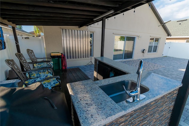 view of patio featuring fence and a sink