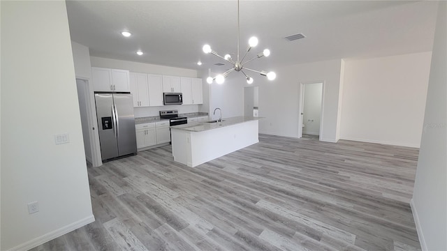 kitchen with visible vents, open floor plan, stainless steel appliances, white cabinetry, and a sink