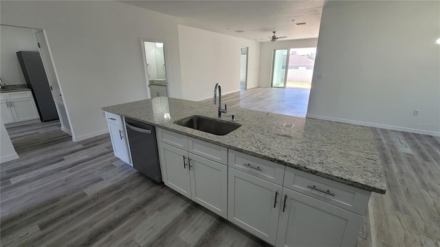 kitchen featuring light wood-type flooring, a sink, open floor plan, white cabinets, and dishwasher