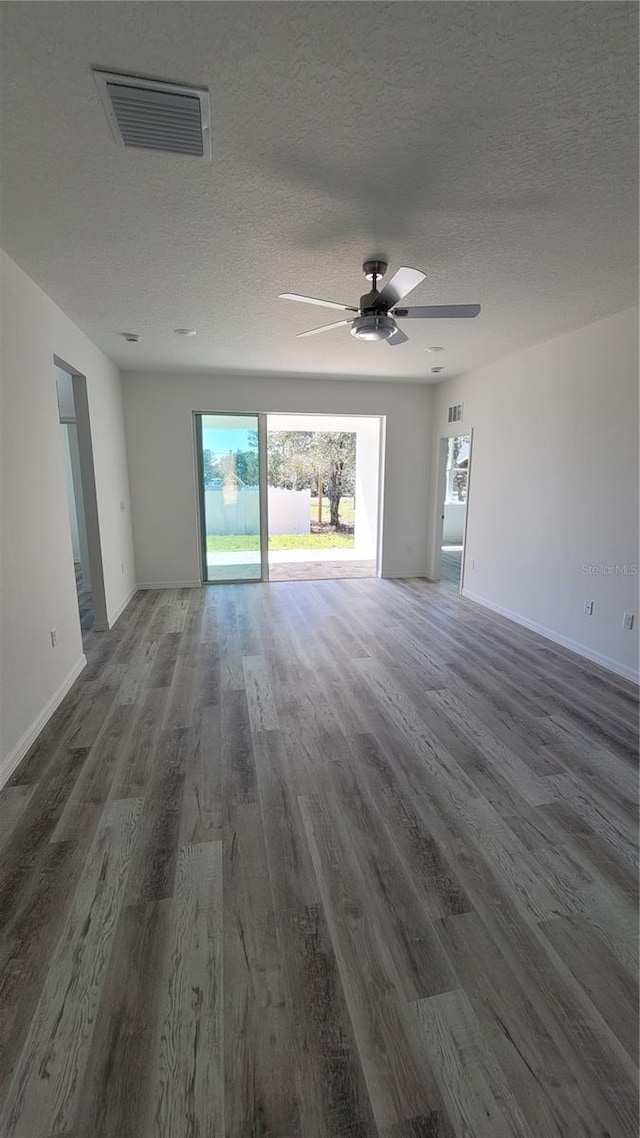 empty room with visible vents, a textured ceiling, ceiling fan, and wood finished floors