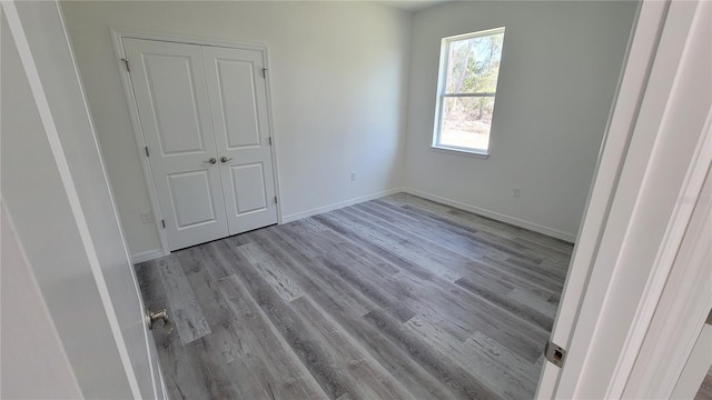 unfurnished bedroom featuring a closet, baseboards, and wood finished floors