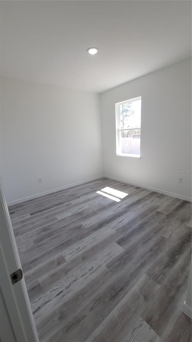 spare room featuring recessed lighting, baseboards, and wood finished floors