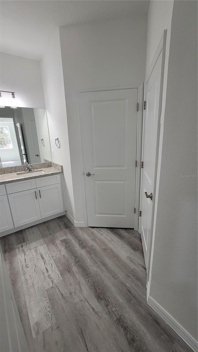 bathroom featuring vanity, wood finished floors, and baseboards