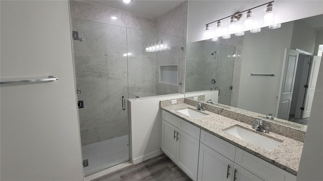 bathroom with double vanity, wood finished floors, a stall shower, and a sink