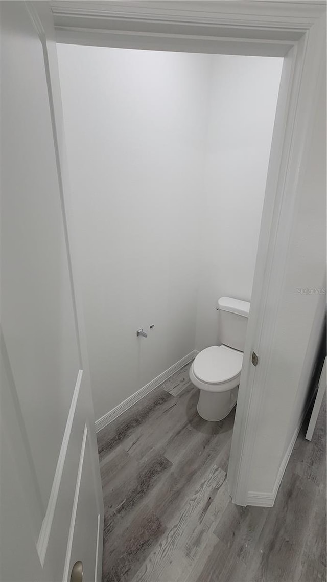 bathroom featuring baseboards, toilet, and wood finished floors