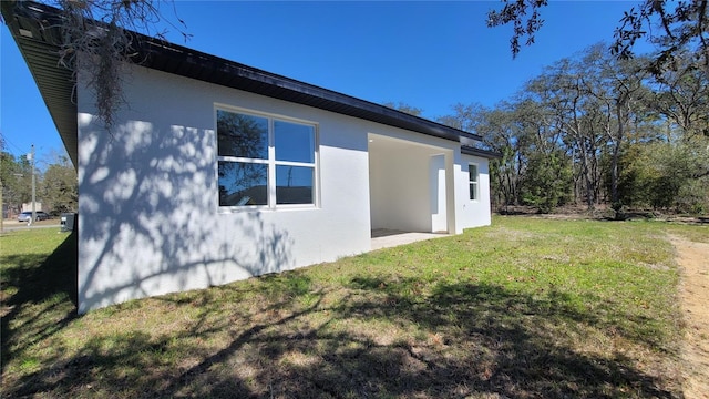 view of side of property featuring stucco siding and a yard