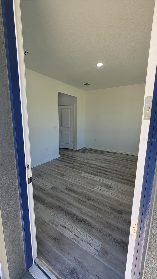 interior space with visible vents, baseboards, dark wood-style flooring, and a textured ceiling