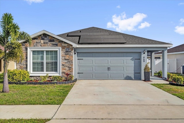 ranch-style house with a front yard, fence, driveway, an attached garage, and roof mounted solar panels