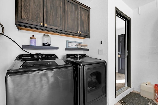 washroom featuring cabinet space, baseboards, and washer and clothes dryer