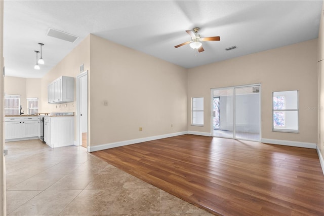 unfurnished living room with light wood finished floors, visible vents, baseboards, and a ceiling fan