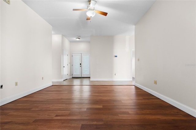 spare room featuring baseboards, wood finished floors, and a ceiling fan