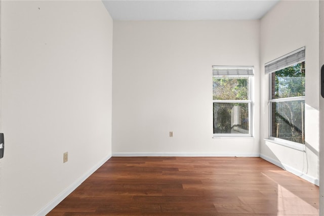 spare room with baseboards and wood finished floors