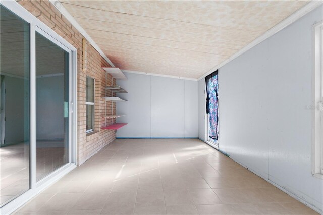 spare room featuring crown molding and brick wall