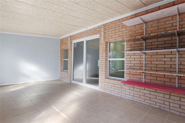 tiled spare room with brick wall and crown molding