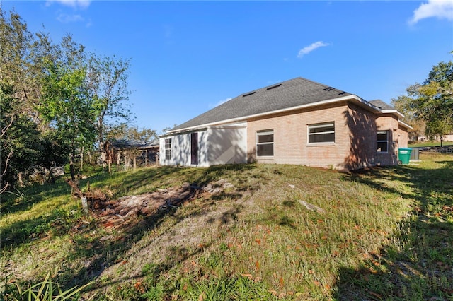 rear view of house featuring brick siding and a lawn