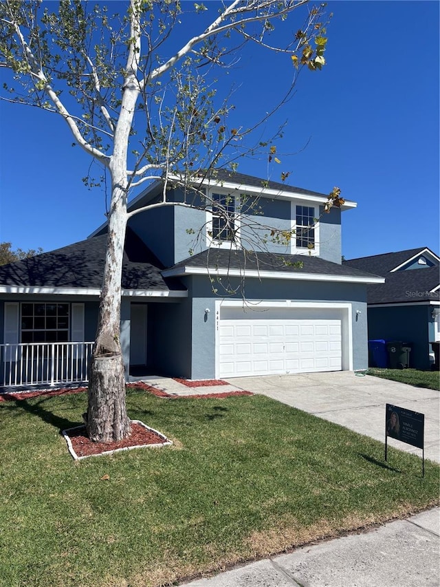 traditional-style house featuring concrete driveway, an attached garage, a front yard, and stucco siding