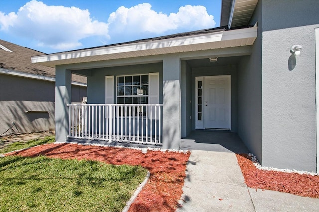 doorway to property featuring stucco siding and covered porch