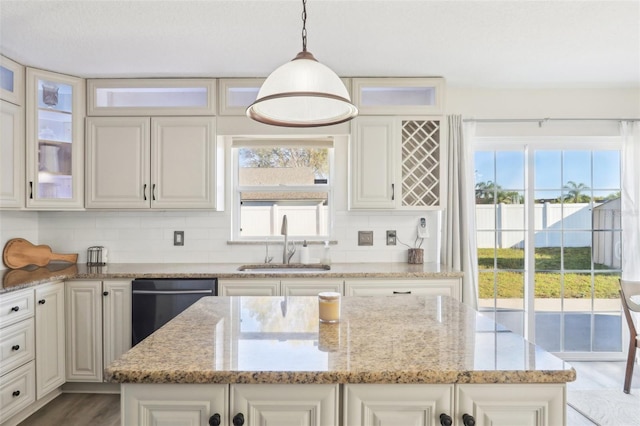 kitchen featuring backsplash, a healthy amount of sunlight, dishwasher, and a sink