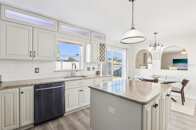 kitchen featuring a sink, stainless steel dishwasher, light wood-style flooring, and a center island