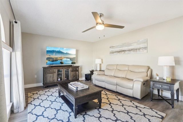 living area featuring baseboards, a ceiling fan, and wood finished floors