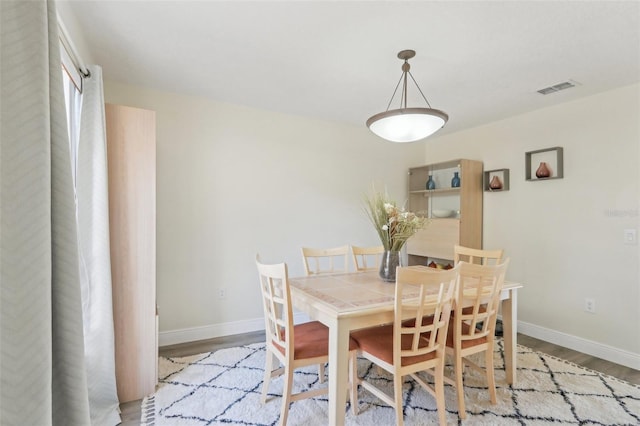 dining space with visible vents, wood finished floors, and baseboards