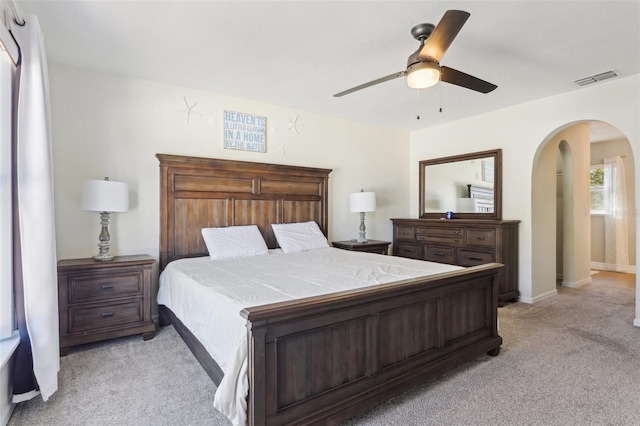 bedroom featuring visible vents, arched walkways, light colored carpet, and a ceiling fan