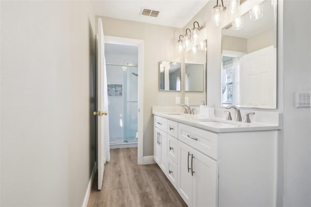 bathroom featuring a sink, visible vents, double vanity, and a shower stall