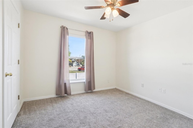 carpeted spare room featuring a ceiling fan and baseboards