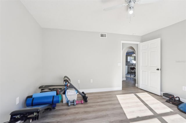 interior space with wood finished floors, visible vents, a ceiling fan, baseboards, and arched walkways