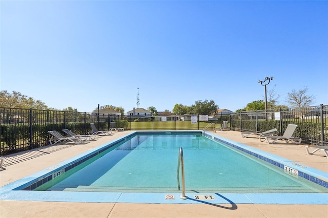 community pool with a patio and fence