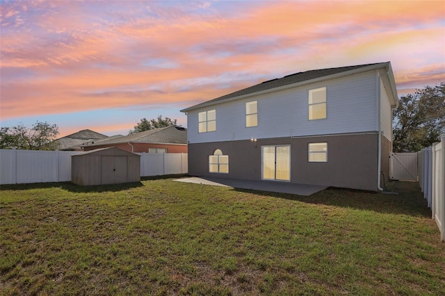 back of house at dusk featuring a patio, a fenced backyard, a shed, a yard, and an outdoor structure