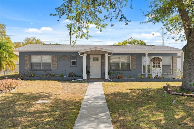 ranch-style house with roof with shingles and a front lawn