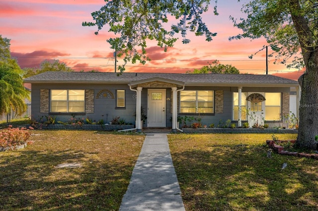 view of front of house featuring a lawn and roof with shingles