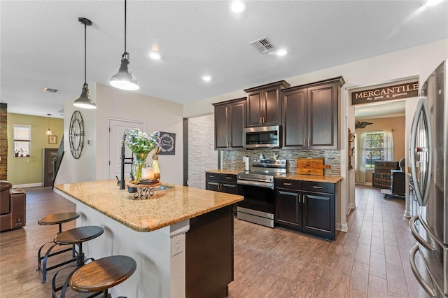 kitchen with light wood-type flooring, tasteful backsplash, visible vents, and stainless steel appliances