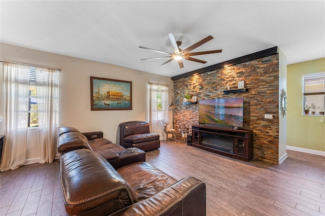 living room featuring a fireplace, baseboards, a ceiling fan, and wood finished floors